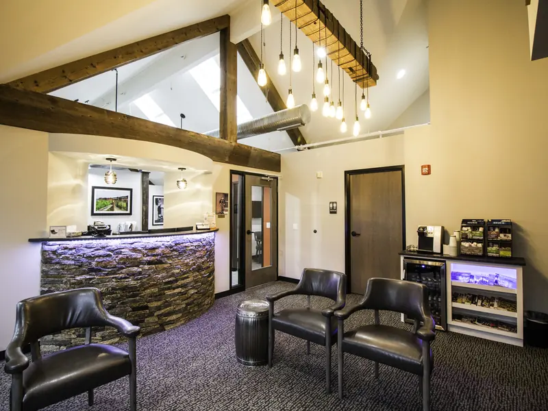 The reception desk at Westport Dental Associates, stone front, exposed beams and pendant lights.