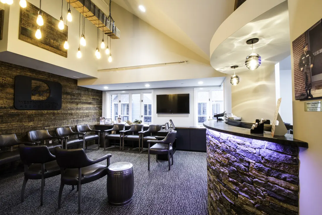 The waiting room at Westport Dental Associates, chairs facing the stone reception desk.