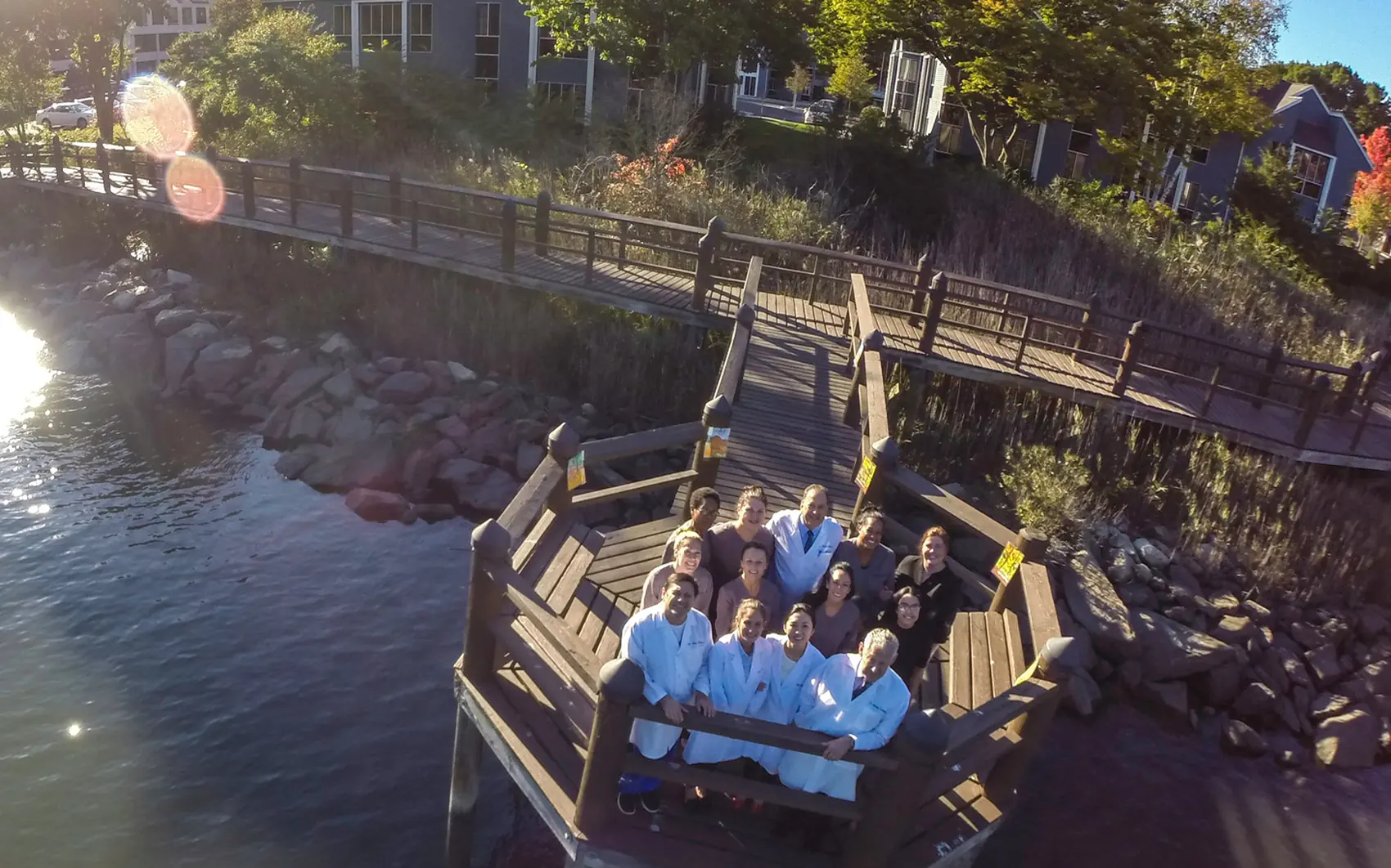 The whole Westport Dental Associates team sitting on the dock behind the practice, out over the Saugatuck River at sunset.